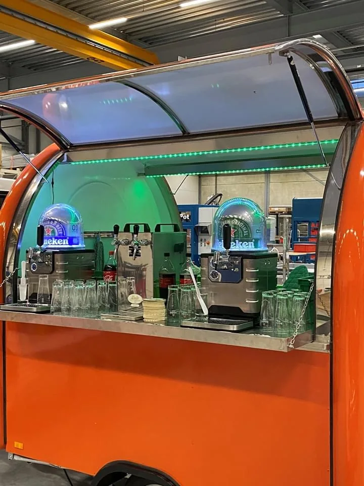 Remorque bar orange ouverte avec deux tireuses à boissons et comptoir inox