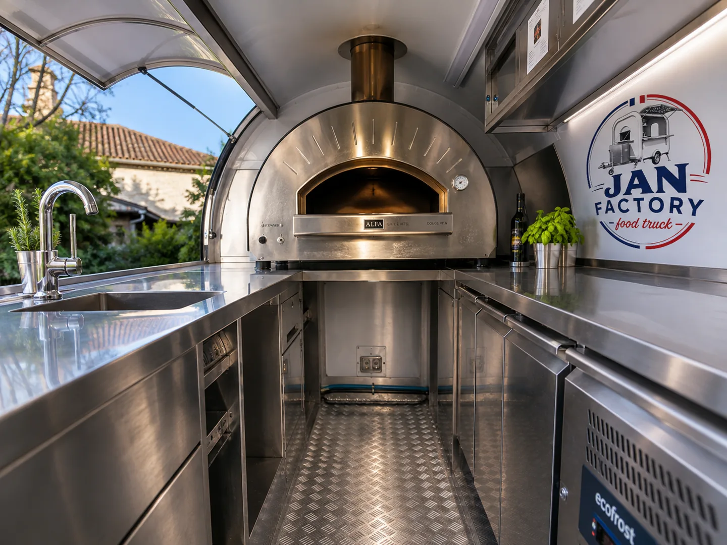 Visuel d’un intérieur de remorque pizza avec four inox, évier, plans de travail et logo JAN FACTORY