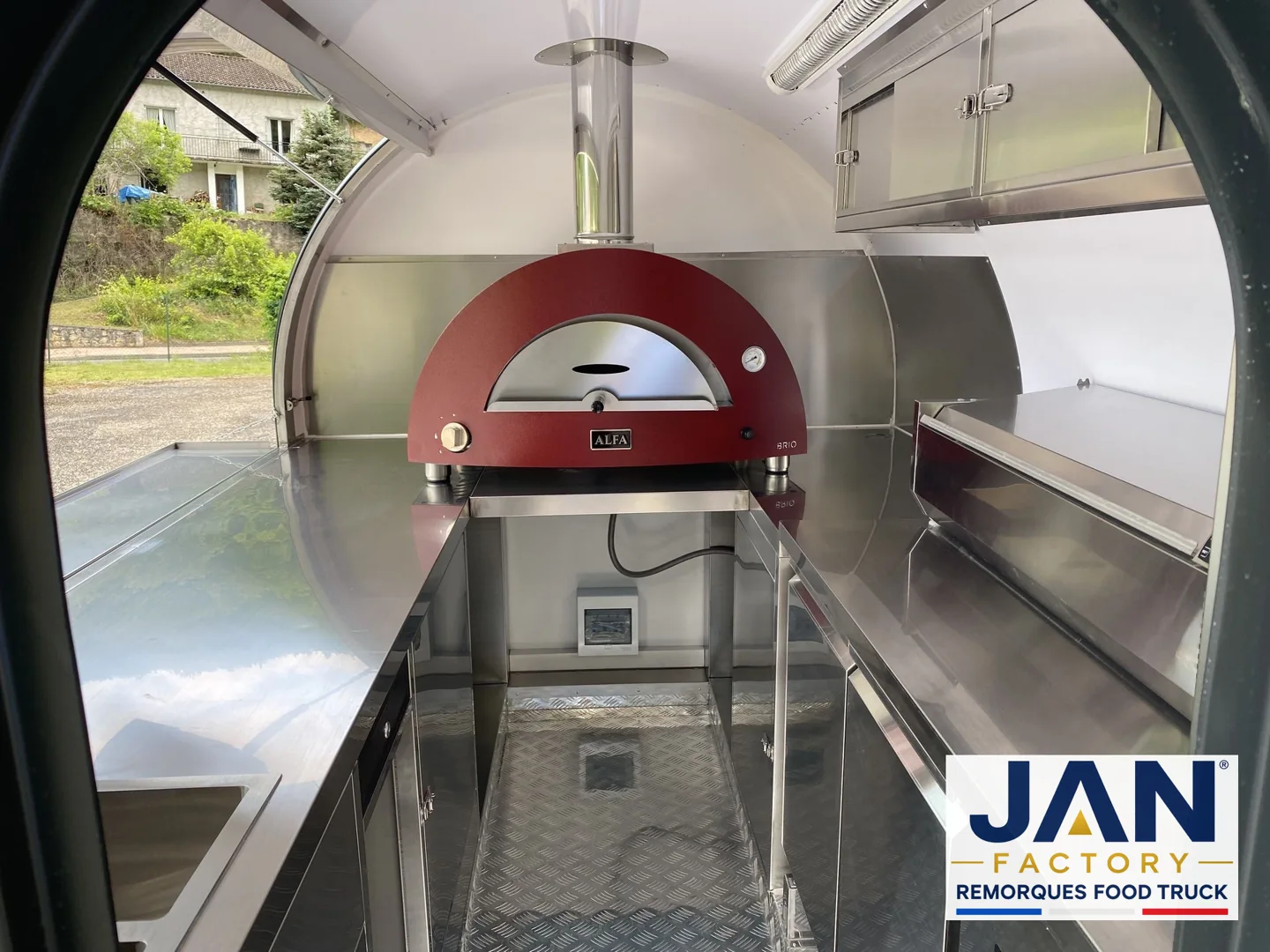 Intérieur de remorque avec four à pizza rouge ALFA Brio, plans de travail inox et logo JAN FACTORY